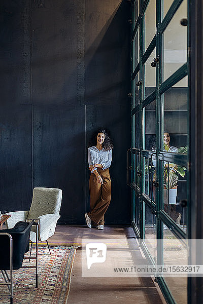 Porträt einer jungen Geschäftsfrau  die am Fenster im Loft-Büro steht