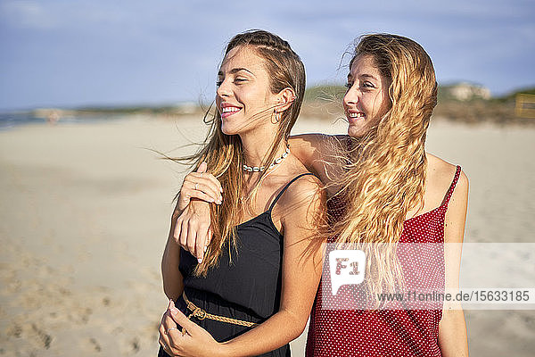 Zwei junge Frauen stehen Arm in Arm am Strand