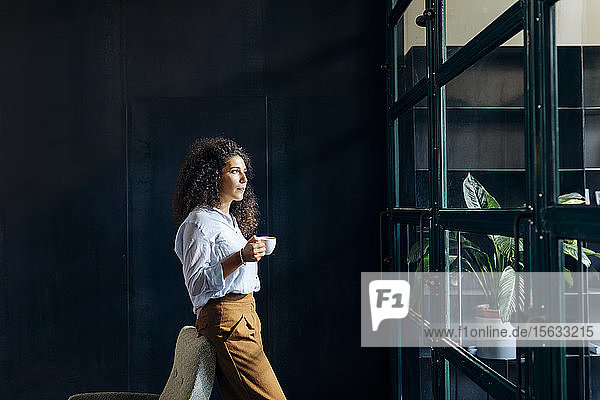 Junge Geschäftsfrau schaut im Loft-Büro aus dem Fenster