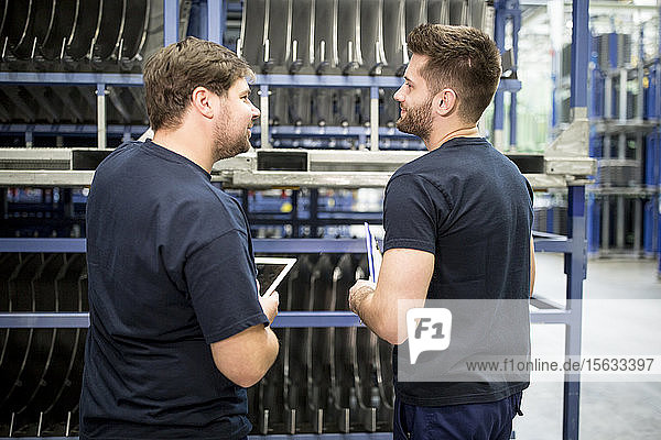 Zwei Arbeiter mit Zwischenablage und Tablette im Fabriklager