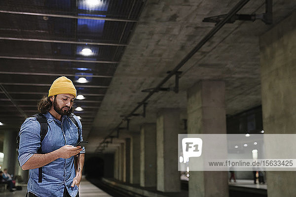 Man waiting at platform using smartphone  Berlin  Germany