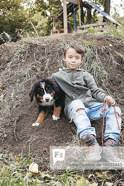 Junge spielt mit seinem Berner Sennenhund im Garten