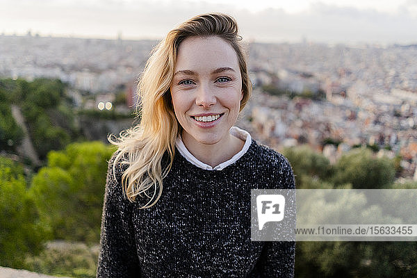 Porträt einer lächelnden jungen Frau bei Sonnenaufgang über der Stadt  Barcelona  Spanien