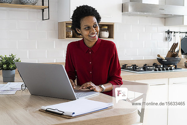 Lächelnde junge Frau benutzt Laptop zu Hause