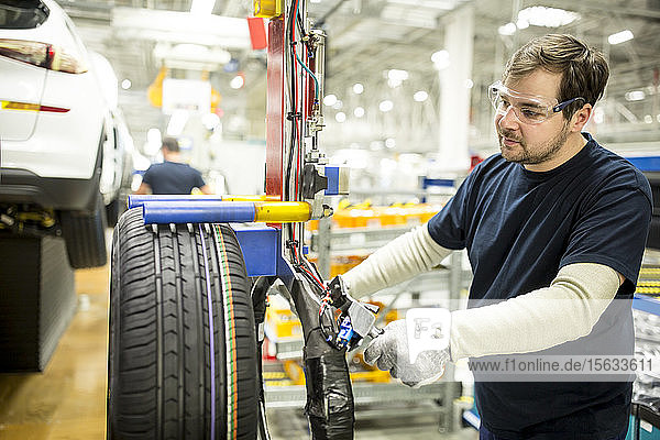 Mann arbeitet an Reifen in moderner Autofabrik