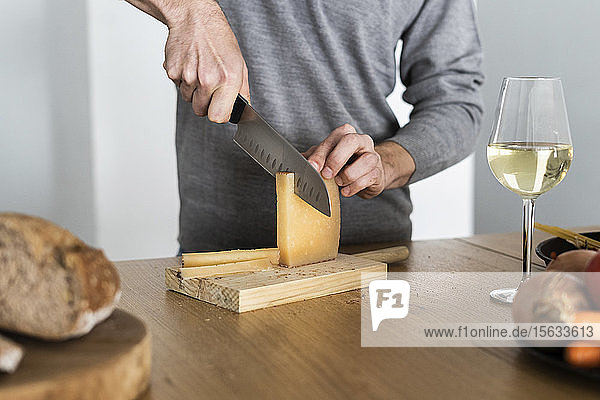 Nahaufnahme eines Mannes  der Käse auf der Küchentheke schneidet