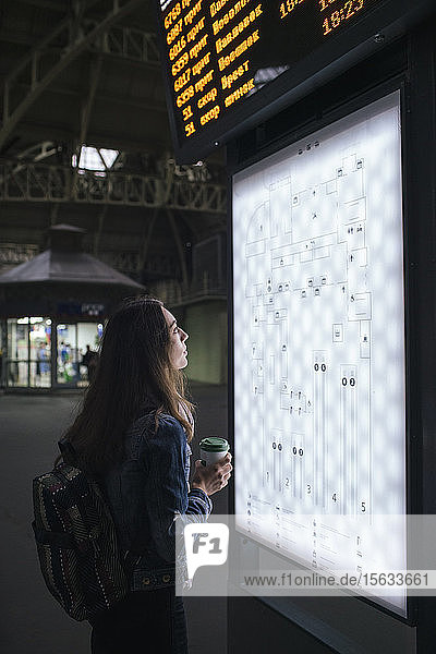 Junge weibliche Reisende mit Kaffee  um sich am Bahnhof an Bord des Reiseziels zu begeben