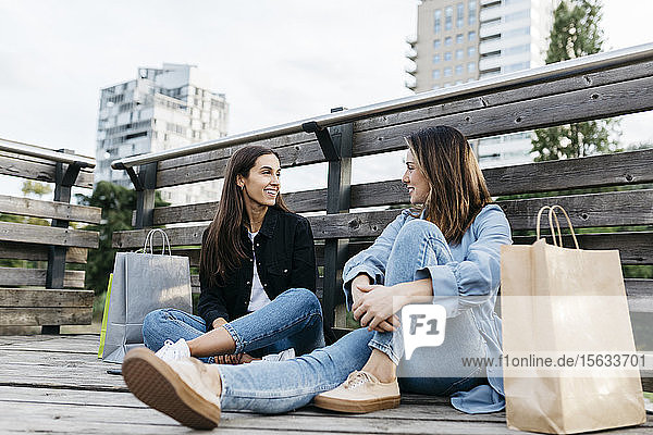 Zwei Freunde  die nach dem Einkaufen auf dem Boden sitzen  mit den Taschen an der Seite