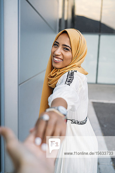 Junge muslimische Frau lächelt und nimmt die Hand eines Mannes  der einen Hidschab trägt