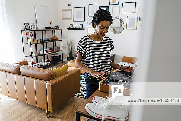 Young woman using record player at home