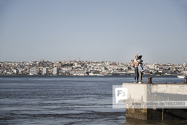 Junges Paar umarmt sich am Pier am Wasser  Lissabon  Portugal