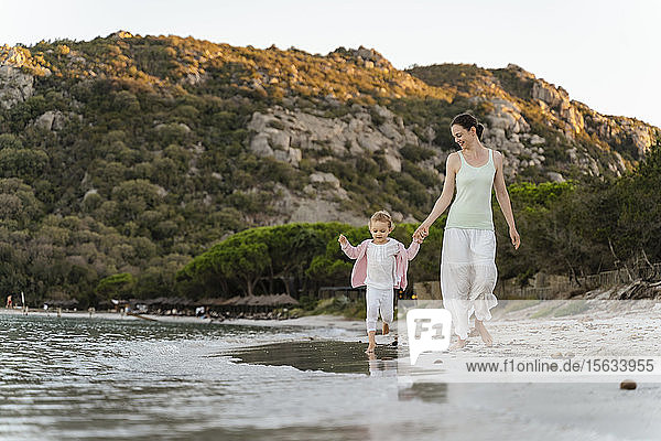 Glückliche Mutter geht mit Tochter am Strand spazieren