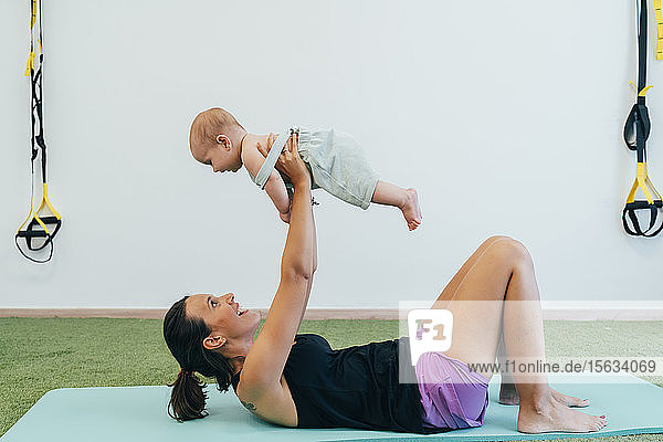 Junge Mutter und Baby üben auf der Yogamatte