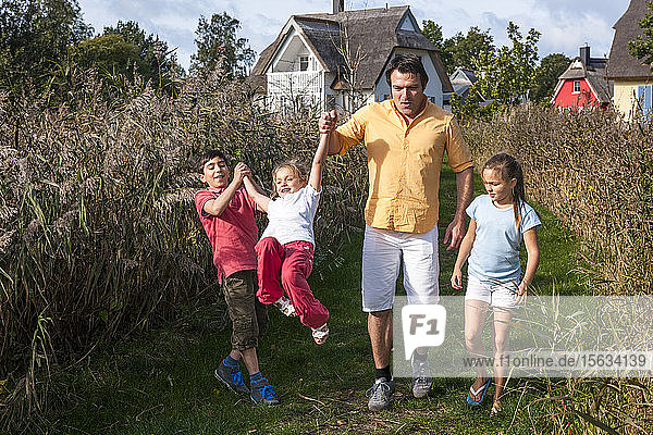 Father with three children walking on a rural path  Darss  Mecklenburg-Western Pomerania  Germany
