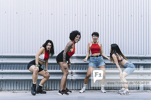 Four young sexy dancing on a strett in front of a wall