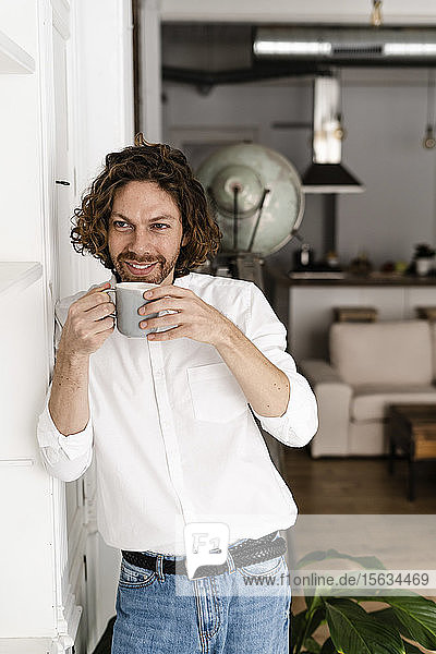 Lächelnder Mann macht zu Hause eine Kaffeepause