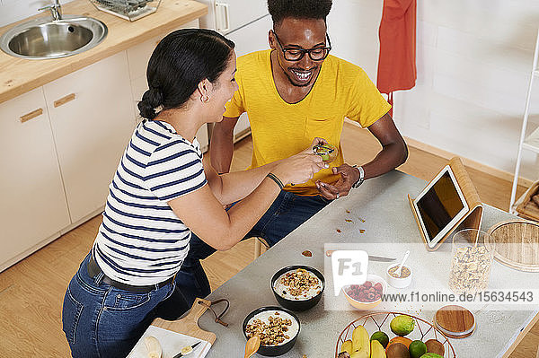 Multiethnisches Paar frühstückt gemeinsam in der Küche  Talbet im Halter