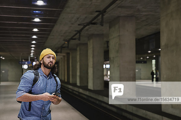 Portrait of man with smartphone waiting at platform  Berlin  Germany