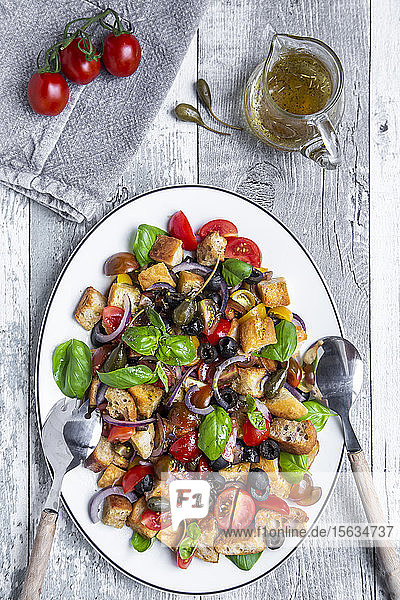 Panzanella  italienischer Brotsalat mit geröstetem Ciabatta  Tomaten  Oliven  roten Zwiebeln  Kapernäpfeln und Basilikum auf Teller