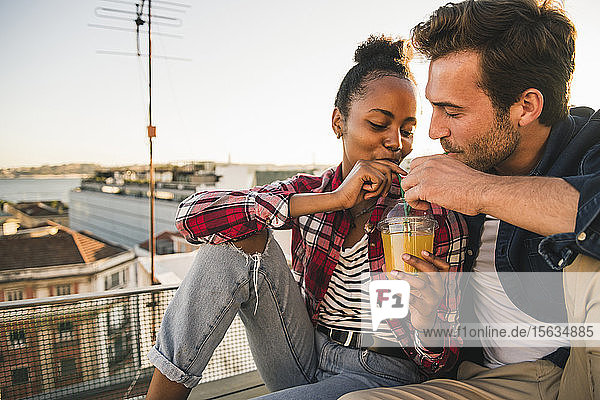 Junges Paar trinkt abends ein Getränk auf dem Dach