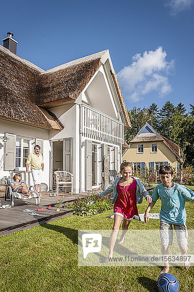 Glückliche Geschwister spielen im Garten Fussball