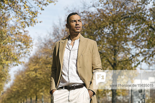 Portrait of pensive businessman standing in the park at autumn