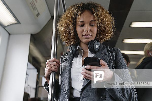 Frau benutzt Smartphone in der U-Bahn