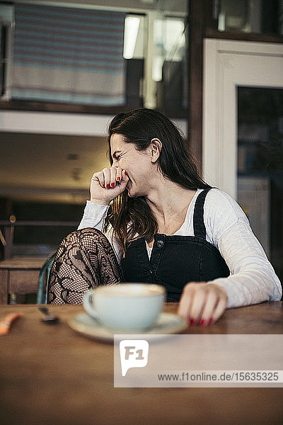 Lachende Frau sitzt in einem Café