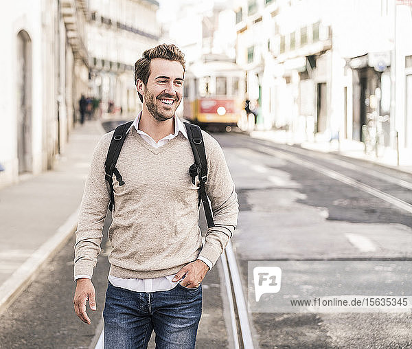 Happy young man with backpack in the city on the go  Lisbon  Portugal