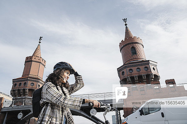 Lächelnde Frau mit Fahrrad in der Stadt an der Oberbaumbrücke  Berlin  Deutschland