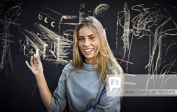 Porträt einer lächelnden jungen Frau vor einer Tafel