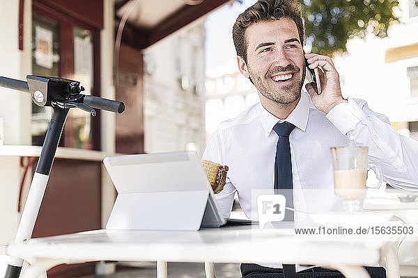 Happy young businessman on the phone at a cafe in the city  Lisbon  Portugal