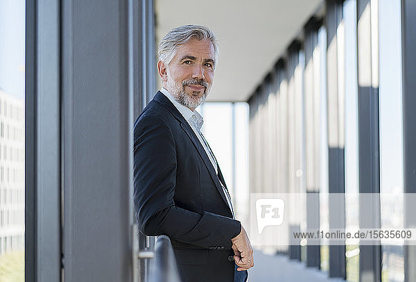 Portrait of mature businessman leaning on railing in a passageway