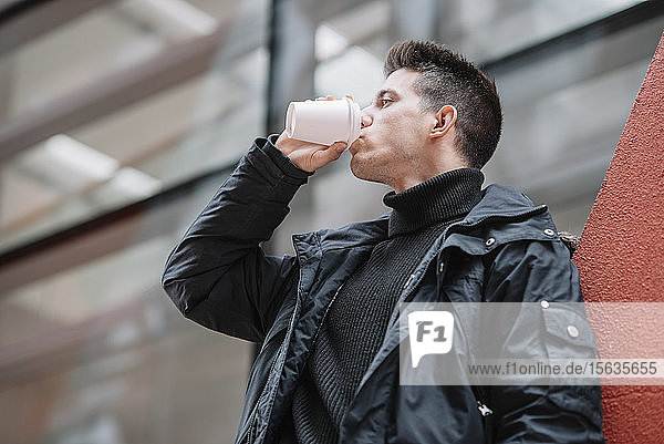 Young man drinking coffee to go in the city