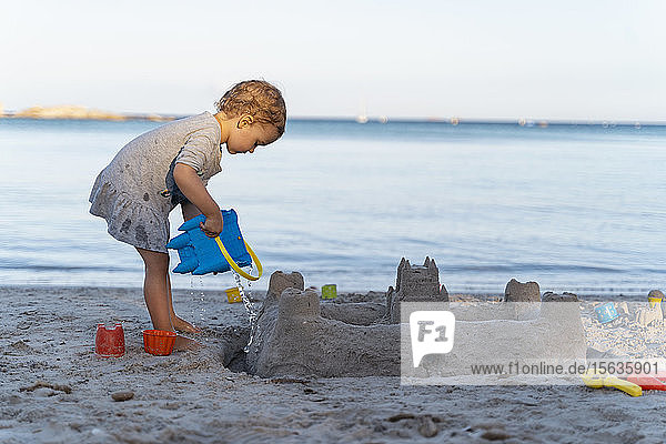 Süßes Kleinkind baut eine Sandburg am Strand