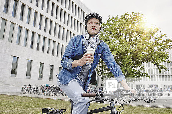 Student mit Kaffee zum Mitnehmen und E-Bike