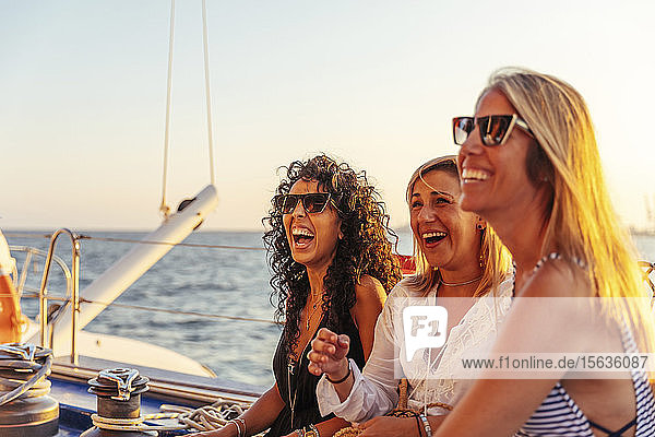 Freunde lachen während der Bootsfahrt im Abendlicht