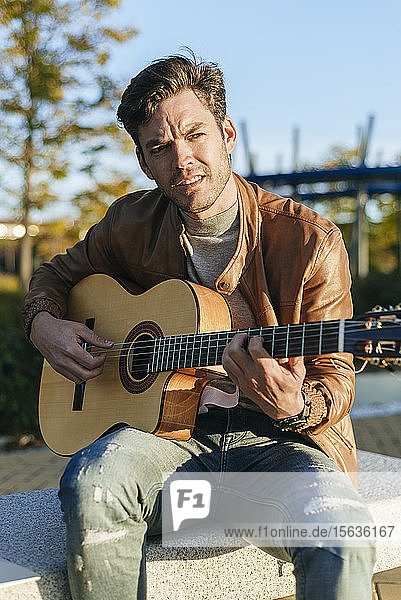 Porträt eines Mannes  der im Freien Gitarre spielt