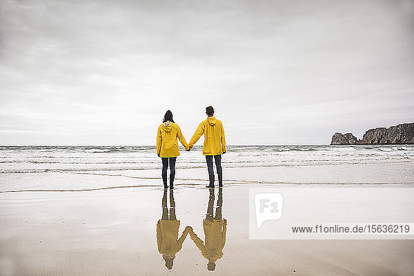Junge Frau in gelben Regenjacken und am Strand stehend  Bretagne  Frankreich