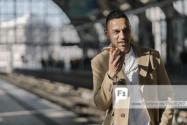 Portrait of businessman on the phone standing on platform of train station Alexanderplatz  Berlin  Germany