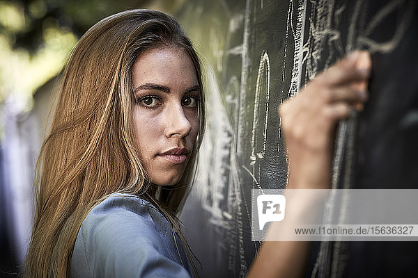 Portrait of a young woman writing on a blackboard