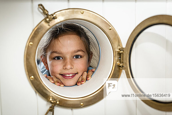 Portrait of smiling girl looking through porthole