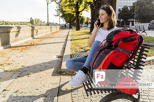 Junge Rucksacktouristin mit rotem Rucksack und Smartphone  auf einem benach in Verona  Italien