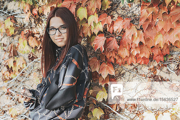Porträt einer Teenagerin mit Smartphone im Herbst