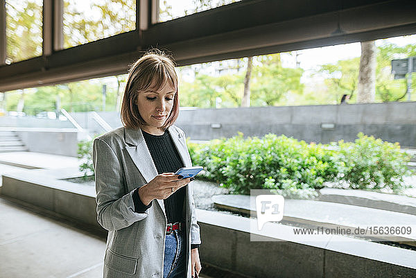 Geschäftsfrau betrachtet Mobiltelefon im Freien