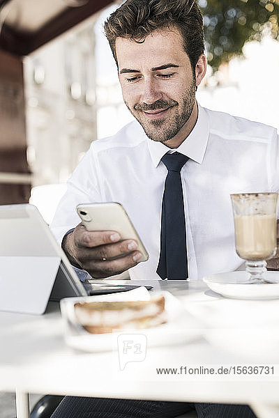 Young businessman using tablet and mobile phone at a cafe in the city  Lisbon  Portugal