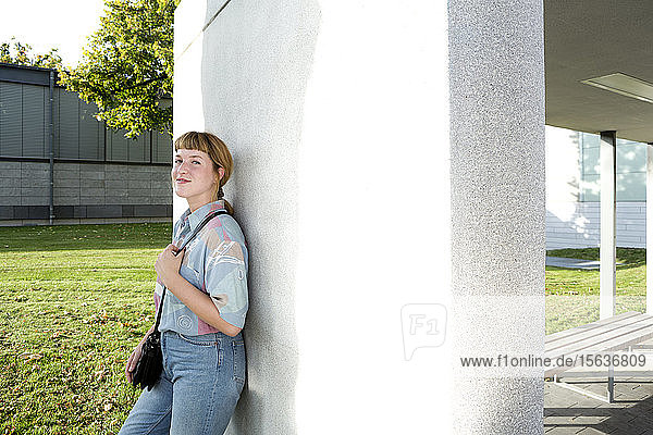 Portrait of smiling young woman leaning against wall