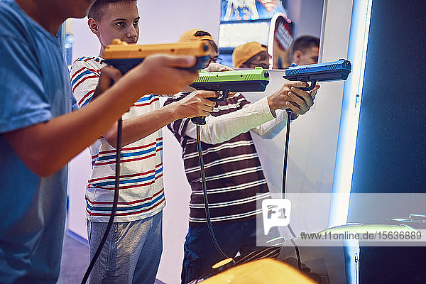 Teenager-Freunde schießen mit Pistolen in einer Spielhalle
