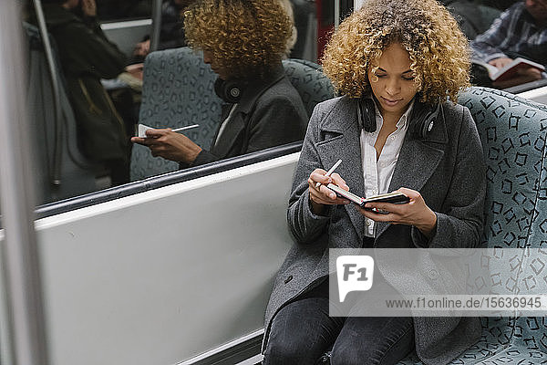Frau macht Notizen in einer U-Bahn