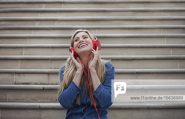 Portrait of smiling woman  listening to music on red headphones